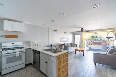 a kitchen with a sink and a living room at BEACHFRONT COTTAGE LOWER UNIT in Oceanside