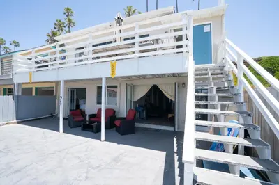 a white house with a staircase leading up to it at BEACHFRONT COTTAGE UPPER UNIT in Oceanside