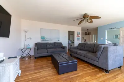 a living room with two couches and a ceiling fan at BEACHFRONT COTTAGE UPPER UNIT in Oceanside