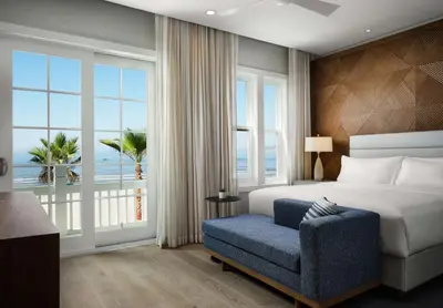 a bedroom with a bed and a chair and a large window at Shore House at The Del, LXR Hotels & Resorts in San Diego
