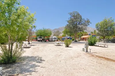 a park with benches and trees and mountains in the background at Palm Canyon Hotel and RV Resort in Borrego Springs