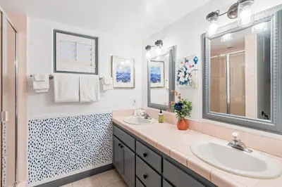 a bathroom with two sinks and two mirrors at The Strand Oasis in Oceanside