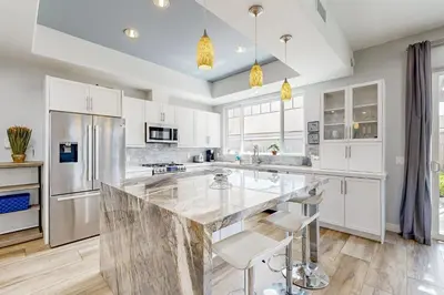 a large kitchen with white cabinets and a large marble counter at Ingraham Delight Pacific Beach in San Diego