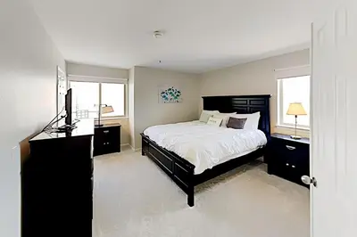 a bedroom with a bed and a television and two windows at Imperial Beach Club in Imperial Beach