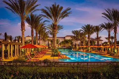 a resort pool with chairs and palm trees at night at Luxury Irvine 2Bedrooms 2Bathrooms kitchen Pool apartment in Irvine