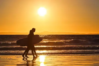 two people walking on the beach at sunset with their surfboards at Cheery Retreat in Newport Beach