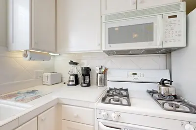 a white kitchen with a stove and a microwave at Cheery Retreat in Newport Beach