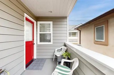 a porch with two chairs and a red door at Cheery Retreat in Newport Beach