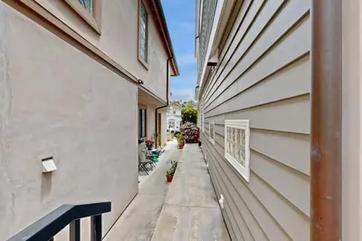 a narrow alley between two buildings with flowers on the side at Cheery Retreat in Newport Beach