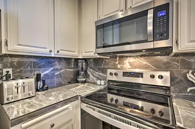 a kitchen with white cabinets and stainless steel appliances at Stunning Oceanside Condo Walk to the Beach! in Oceanside