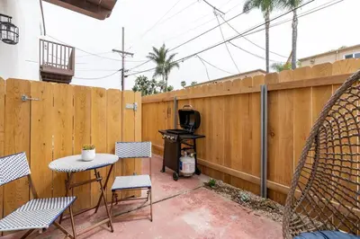 a patio with a grill and chairs and a fence at The Rosemont III - La Jolla Luxury in San Diego