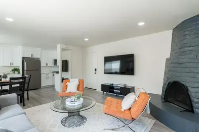 a living room with orange chairs and a fireplace at The Rosemont III - La Jolla Luxury in San Diego