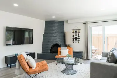 a living room with a stone fireplace and orange chairs at The Rosemont III - La Jolla Luxury in San Diego