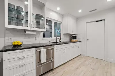 a white kitchen with white cabinets and a sink at The California III in San Diego