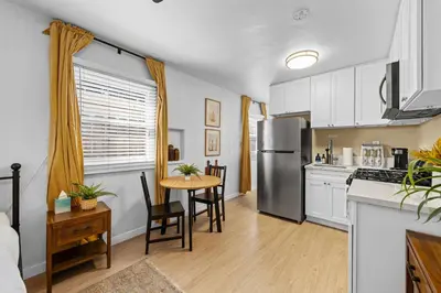 a kitchen with a table and a stainless steel refrigerator at Live like a local - Studio with huge backyard in San Diego