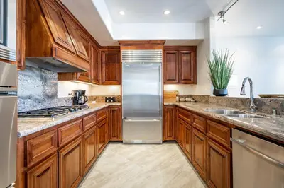 a kitchen with wooden cabinets and a stainless steel refrigerator at Your Home in San Diego - Two-Car Garage in San Diego