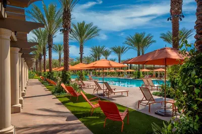 a resort pool with chairs and umbrellas and palm trees at Luxury Irvine Spectrum 2 bedrooms 2 Bathrooms Kitchen pool Apartment in Irvine