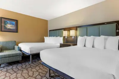 a hotel room with two beds and a chair at Best Western Plus Oceanside Palms in Oceanside
