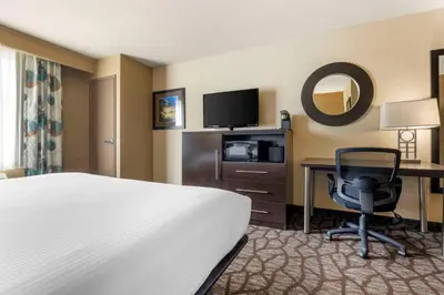 a hotel room with a bed and a desk with a computer at Best Western Plus Oceanside Palms in Oceanside