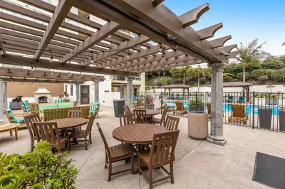 a patio with tables and chairs under a wooden pergola at Seacliff Retreat in Oceanside