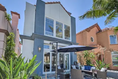 a blue and white house with an umbrella and chairs at Oceanside Home with Rooftop Patio - Steps to Beach! in Oceanside