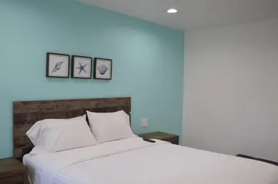 a bedroom with a white bed with three pictures on the wall at Calafia Inn San Clemente Newly renovated in San Clemente