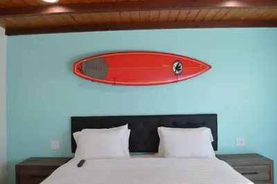a surfboard hanging on a wall above a bed at Calafia Inn San Clemente Newly renovated in San Clemente
