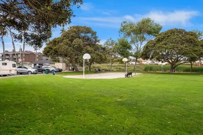 a park with green grass and trees and a basketball hoop at Buccaneer Beach Lookout - 30-Night Minimum in Oceanside