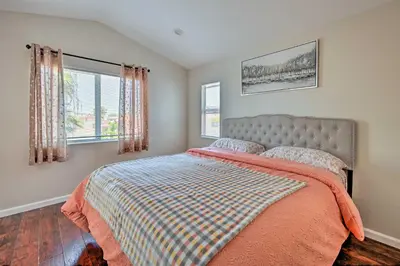 a bedroom with a bed with a orange blanket and two windows at Karaoke Fun, Hot Tub and Patio! San Diego Sanctuary in San Diego