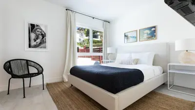 a white bedroom with a bed and a chair at Avalon 2 Unit Buyout II IV by AvantStay Mins to Gaslamp Patio w BQQ in San Diego