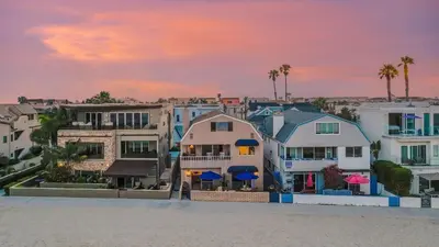 a group of houses on the beach at sunset at Bay View I by AvantStay Stylish Mission Beach Home on the Sand in San Diego