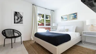 a white bedroom with a bed and a chair at Avalon Buyout by AvantStay Mins to Gaslamp Rooftop w BBQ Patio in San Diego
