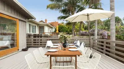 a wooden table with white chairs and an umbrella on a deck at Camden by AvantStay 5mins to the Beach Elevated Home w Pacific Ocean Views in Encinitas