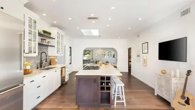 a kitchen with white cabinets and a flat screen tv at Vista Del Mar by AvantStay Stunning Spanish Inspired Home w Pool Hot Tub Rooftop Patio in San Diego