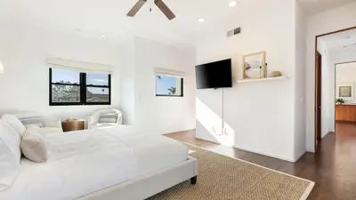 a white bedroom with a large bed and a flat screen tv at Vista Del Mar by AvantStay Stunning Spanish Inspired Home w Pool Hot Tub Rooftop Patio in San Diego