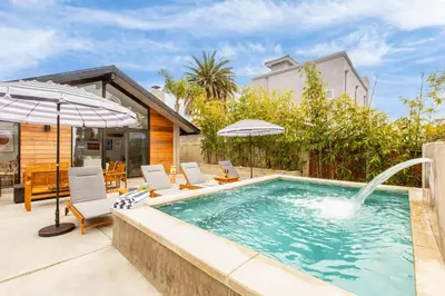a swimming pool with chairs and an umbrella at Hamilton I by AvantStay Beach House Rooftop Deck Newly Renovated Bungalow in San Diego