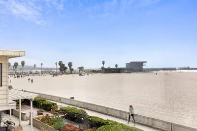 a person walking on a beach near the water at Shoreline by AvantStay Spectacular Beachfront Home w Fire Pit Spa Pool Table in San Diego