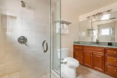 a bathroom with a toilet and a glass shower at Shoreline by AvantStay Spectacular Beachfront Home w Fire Pit Spa Pool Table in San Diego