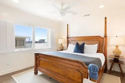 a bedroom with a large wooden bed with blue pillows at Shoreline by AvantStay Spectacular Beachfront Home w Fire Pit Spa Pool Table in San Diego