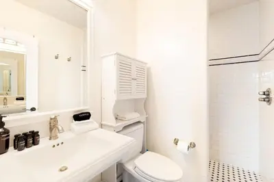 a white bathroom with a toilet and a sink at Shoreline by AvantStay Spectacular Beachfront Home w Fire Pit Spa Pool Table in San Diego