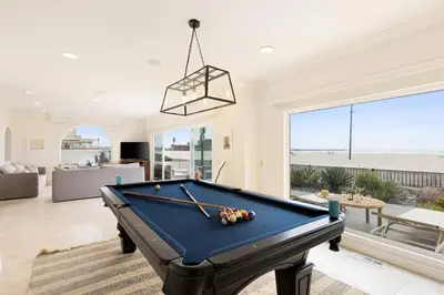 a pool table in a living room with a view of the beach at Shoreline by AvantStay Spectacular Beachfront Home w Fire Pit Spa Pool Table in San Diego