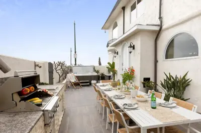 an outdoor patio with a long table and a grill at Shoreline by AvantStay Spectacular Beachfront Home w Fire Pit Spa Pool Table in San Diego