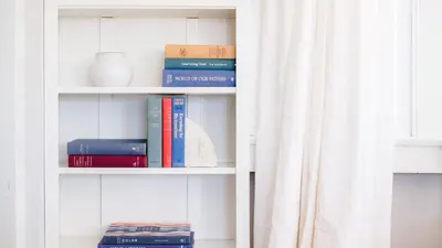a book shelf with books on it next to a window at Topaz By AvantStay Adorable Cottage Walking Distance to Beach w Large Patio in San Diego