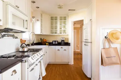 a kitchen with white cabinets and a white stove top oven at Kokomo by AvantStay Bayside Getaway w Fire Pit Large Outdoor Patio in San Diego
