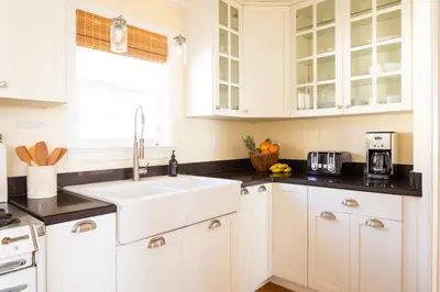 a kitchen with white cabinets and a sink at Kokomo by AvantStay Bayside Getaway w Fire Pit Large Outdoor Patio in San Diego