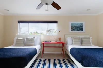 two beds in a room with a red table at Oliver by AvantStay Summer Escape Beach House 4 Blcks from Ocean in San Diego