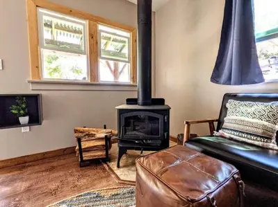 a living room with a fireplace and a leather couch at #6 The Hawks Hideout Cabin in Santa Ysabel