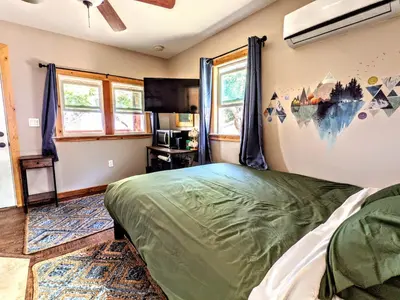 a bedroom with a green bed in a room with windows at Falcon's Chalet- Cabin in Santa Ysabel