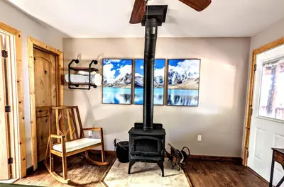 a fireplace in a room with a chair and paintings at Falcon's Chalet- Cabin in Santa Ysabel