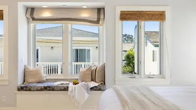 a bedroom with a window seat with a view of a house at Crystal Cove by AvantStay Gorgeous Charming Newport Home in Newport Beach